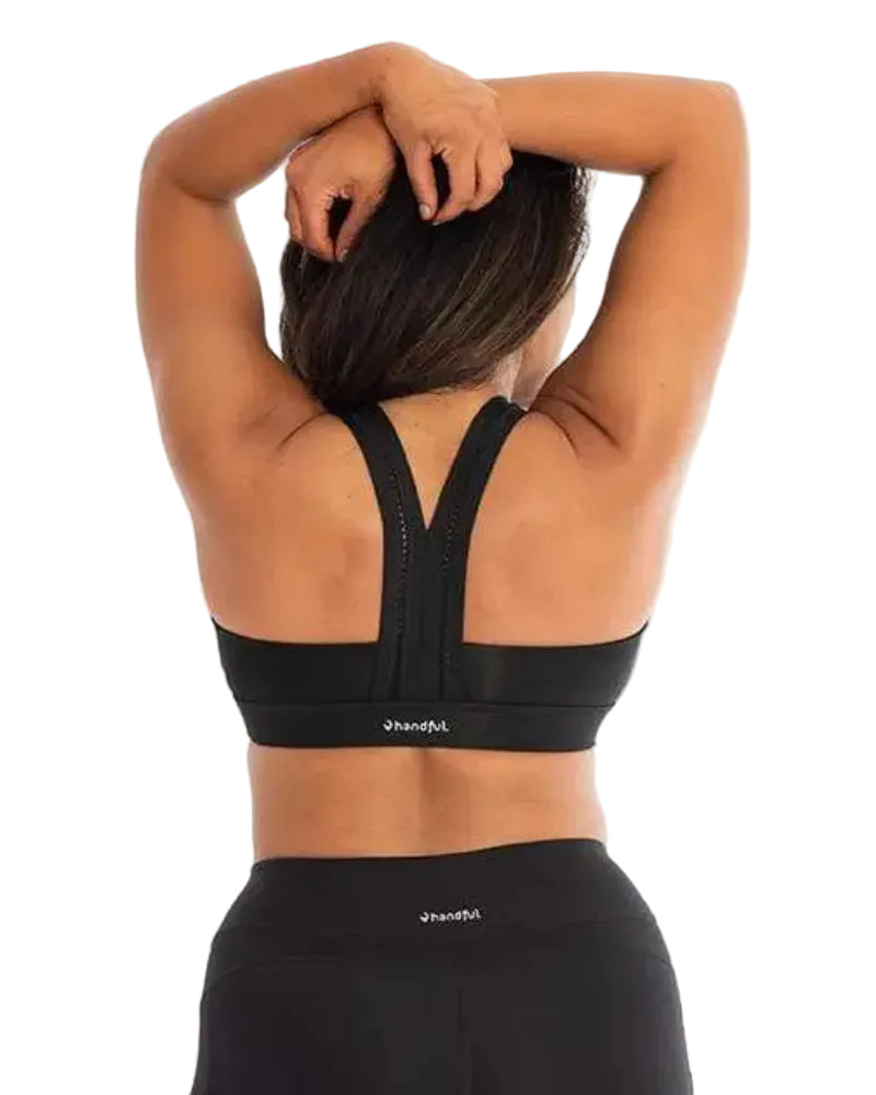 Person wearing a black sports bra and leggings with 'bandful' branding on a light gray background