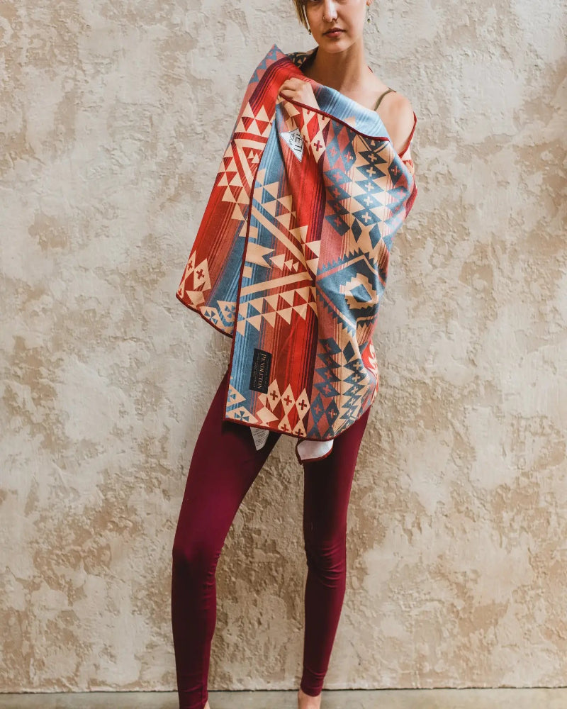 Person holding a colorful patterned towel against a textured wall
