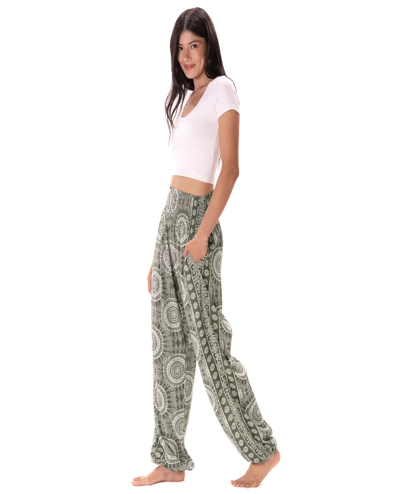 Woman wearing green patterned pants and a white top on a white background