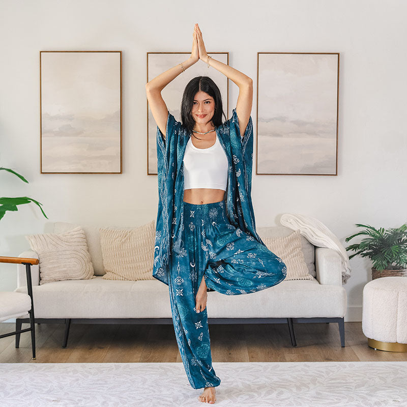 Woman in blue patterned outfit practicing yoga in a living room.