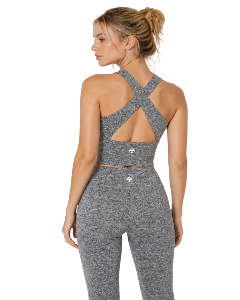 Woman wearing a gray athletic outfit with cut-out design on a light gray background