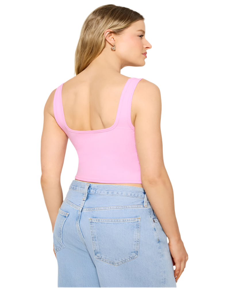 Woman wearing a pink crop top and blue jeans on a white background