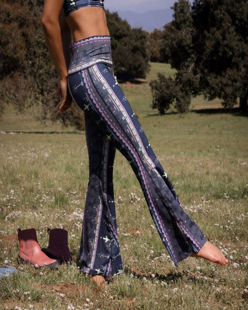 Person wearing patterned flared pants in a natural setting with trees and grass.