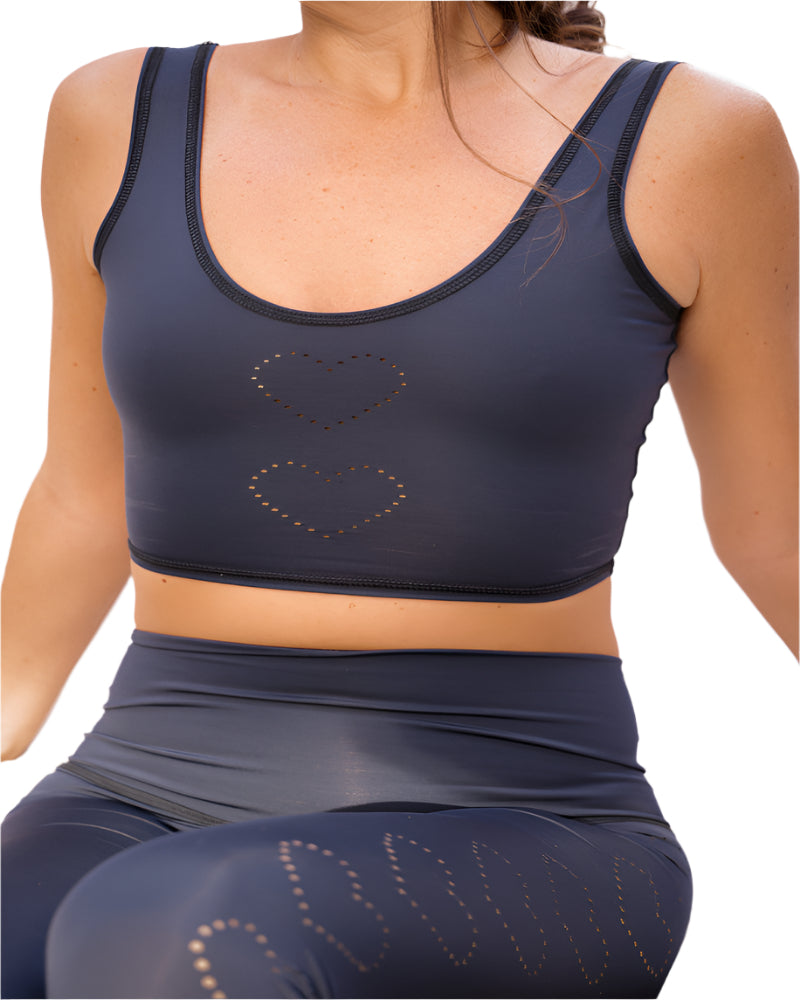 Person wearing a navy blue sports bra and leggings with heart designs.