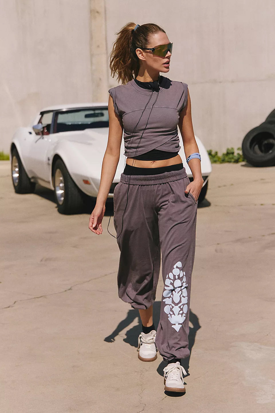Woman in a gray sleeveless top and pants with floral design walking outdoors.