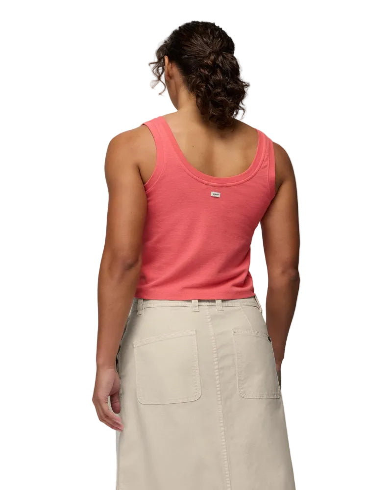 Person wearing a pink tank top and beige pants on a plain background