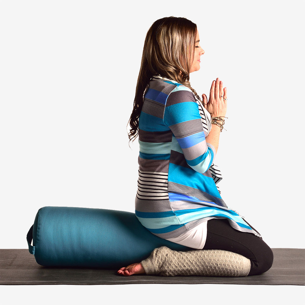 Woman in a yoga pose with a yoga bolster on a white background