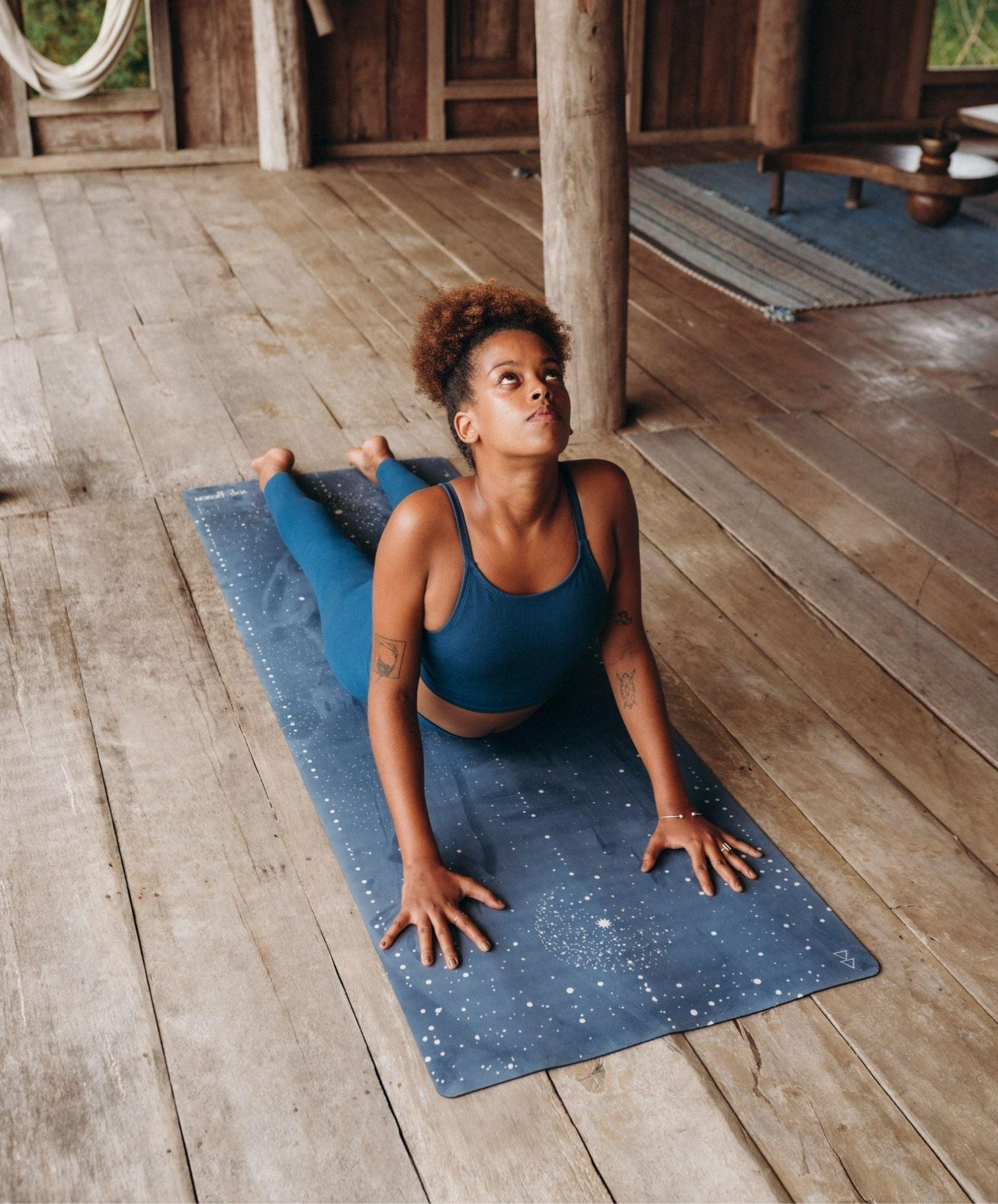 Woman in blue athletic wear practicing yoga on a wooden floor.