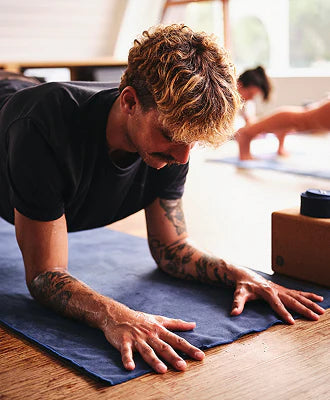 Man practicing yoga on a blue mat with a blurred background