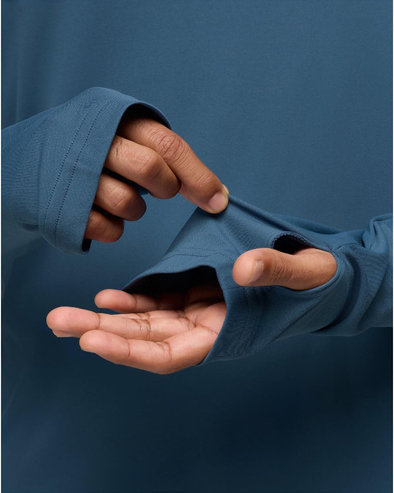 Close-up of a person wearing a blue jacket with sleeves pulled up, showing hands.