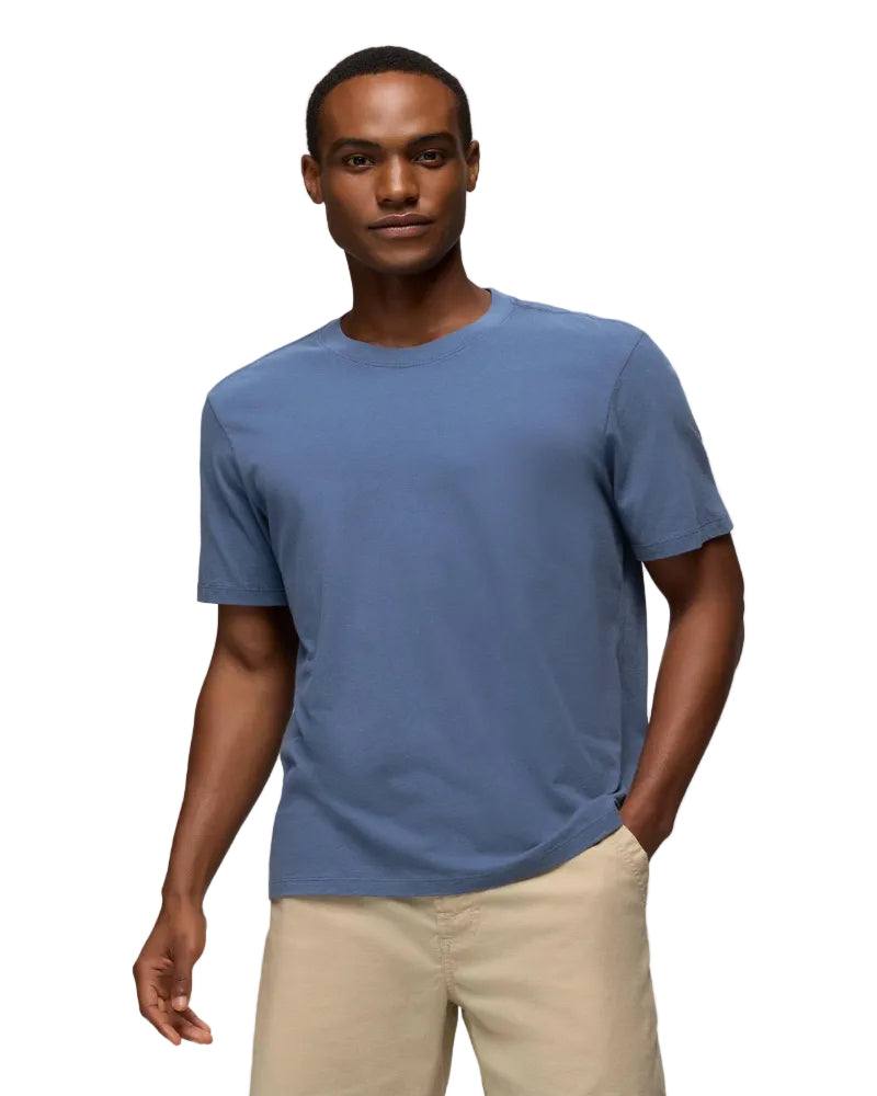 Man wearing a blue t-shirt and beige pants against a light gray background