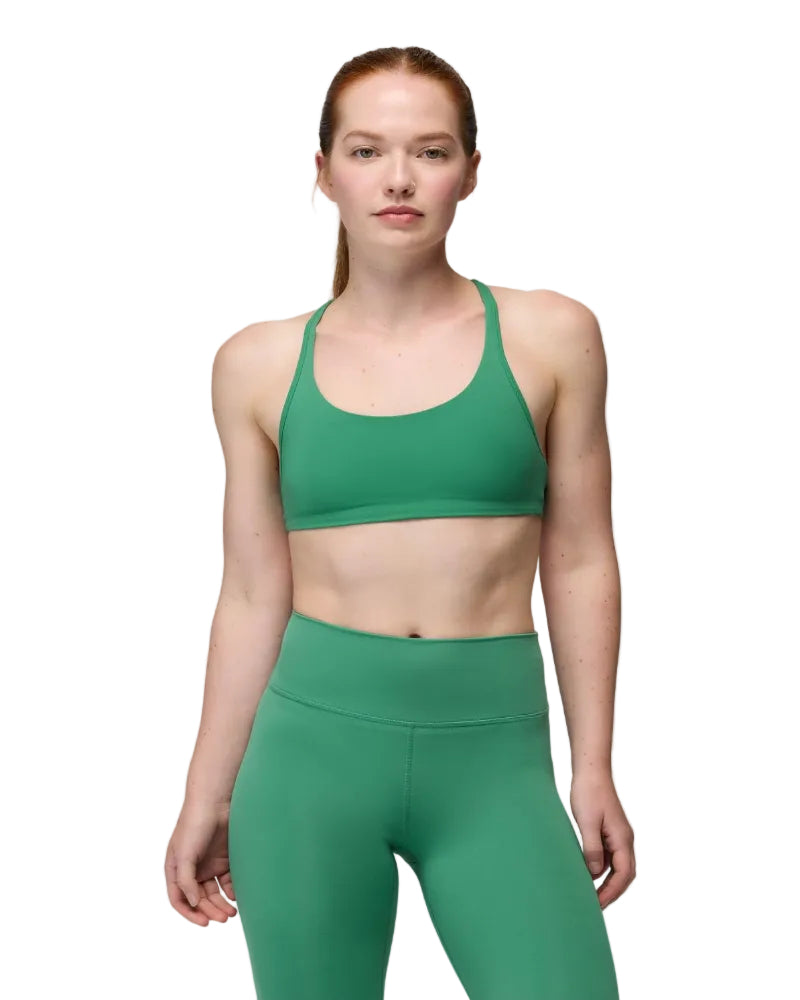 Woman wearing a green sports bra and leggings on a gray background