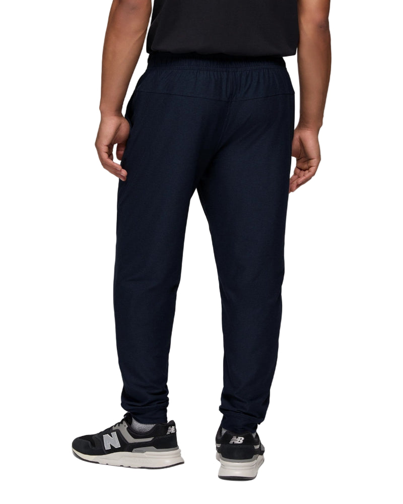 Person wearing navy jogger pants and black sneakers on a white background