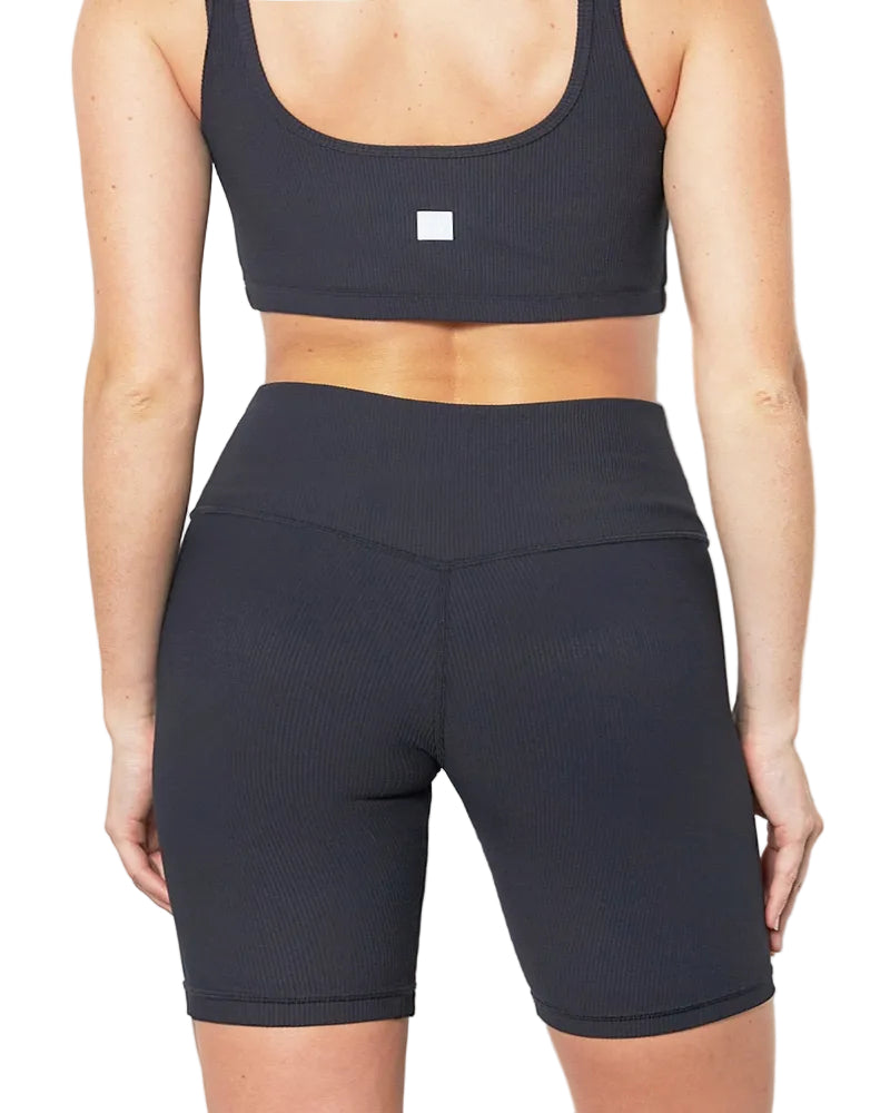Person wearing a black sports bra and shorts set on a plain background