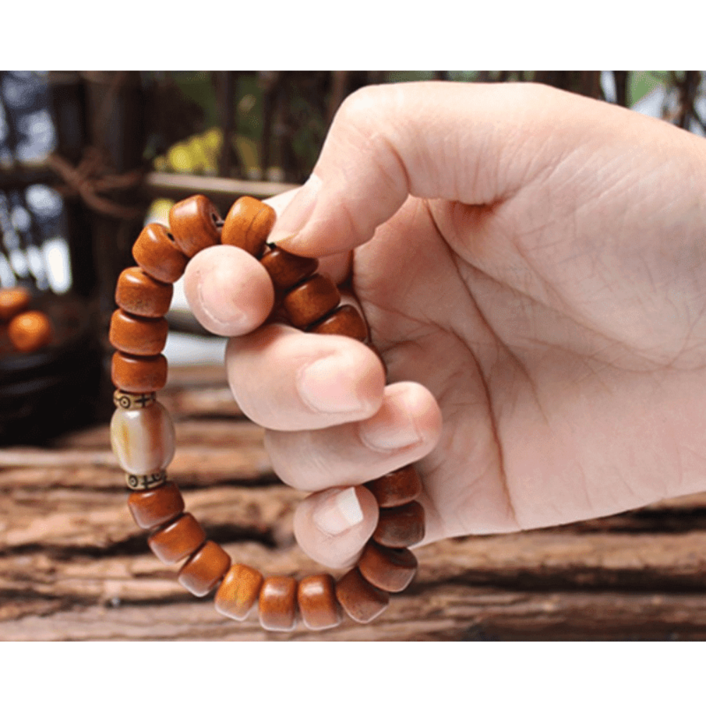 Wooden beaded bracelet with a central cream bead on a white background