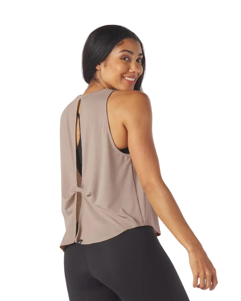 Woman wearing a beige sleeveless top with open back on a white background