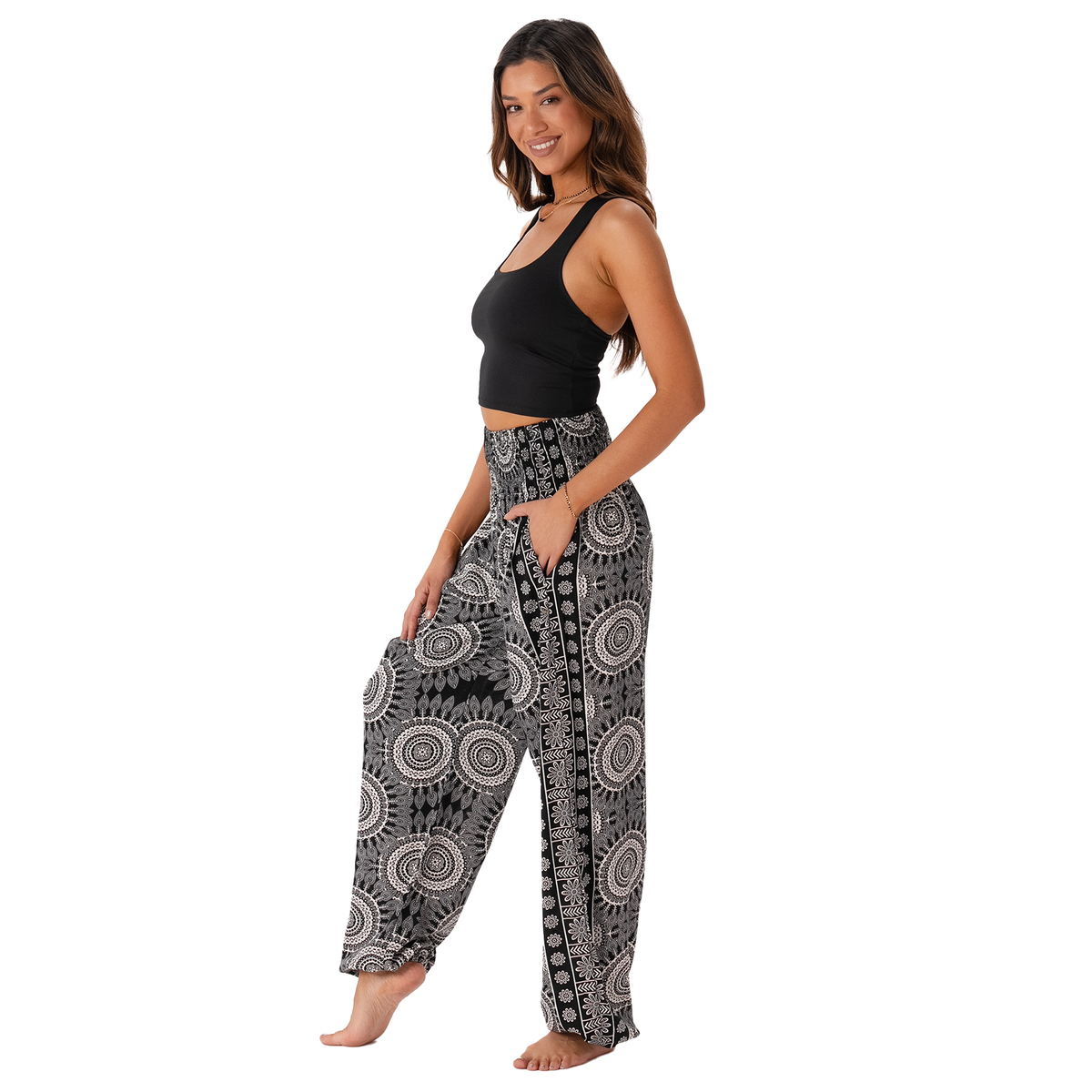 Woman wearing black and white patterned harem pants on a white background
