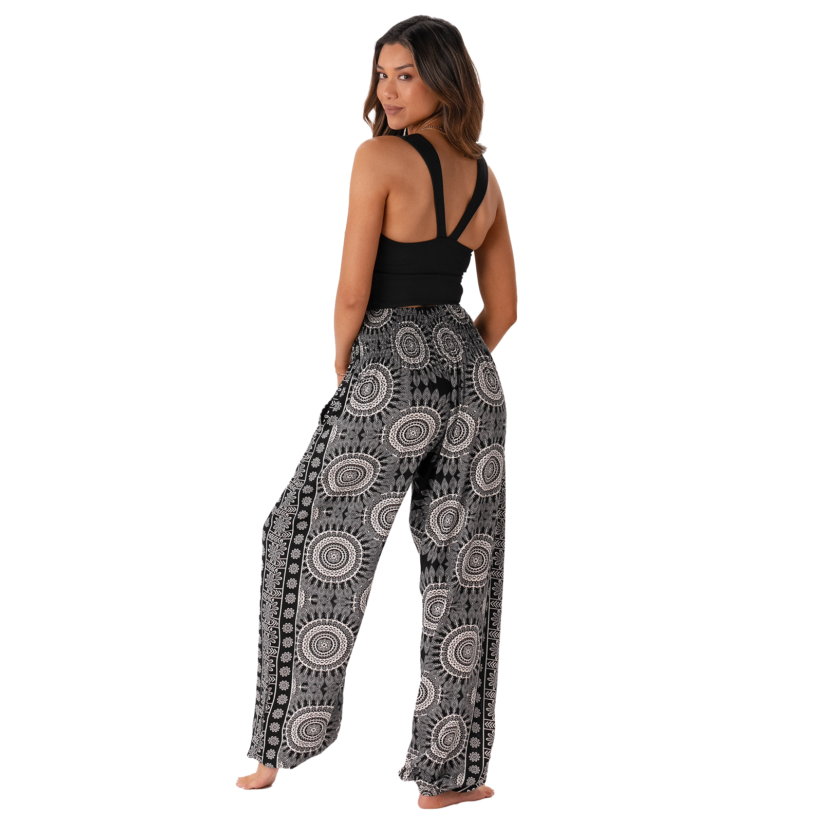 Woman wearing a black tank top and patterned pants on a white background