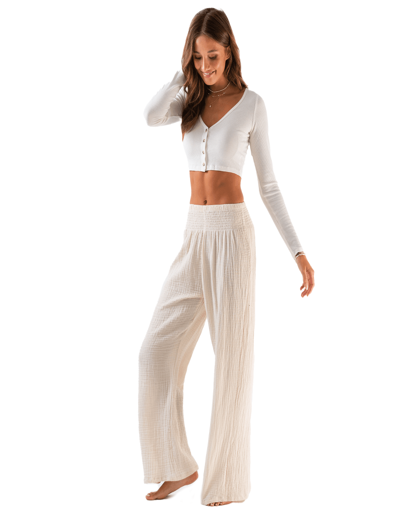Woman wearing a white long-sleeve crop top and beige wide-leg pants on a white background