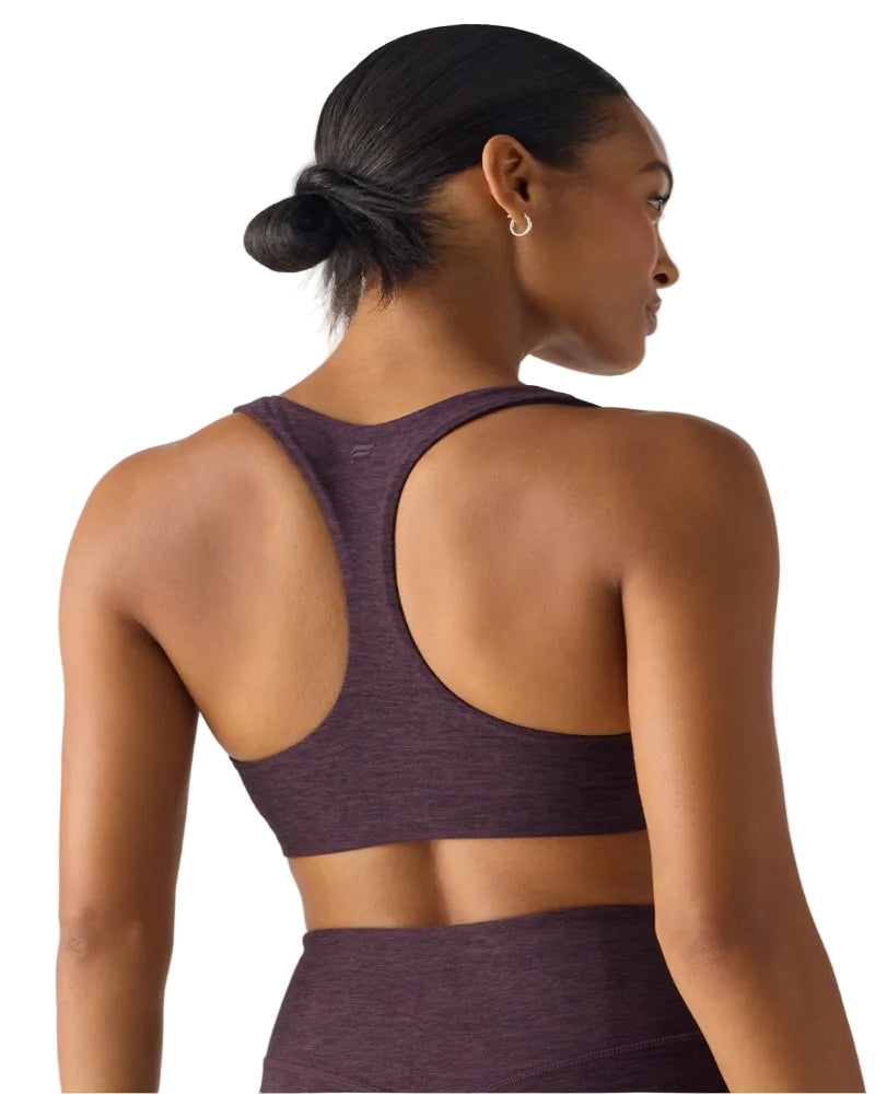 Woman wearing a purple sports bra and leggings on a white background