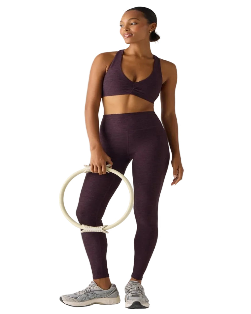 Woman in purple athletic wear holding a white hula hoop on a white background