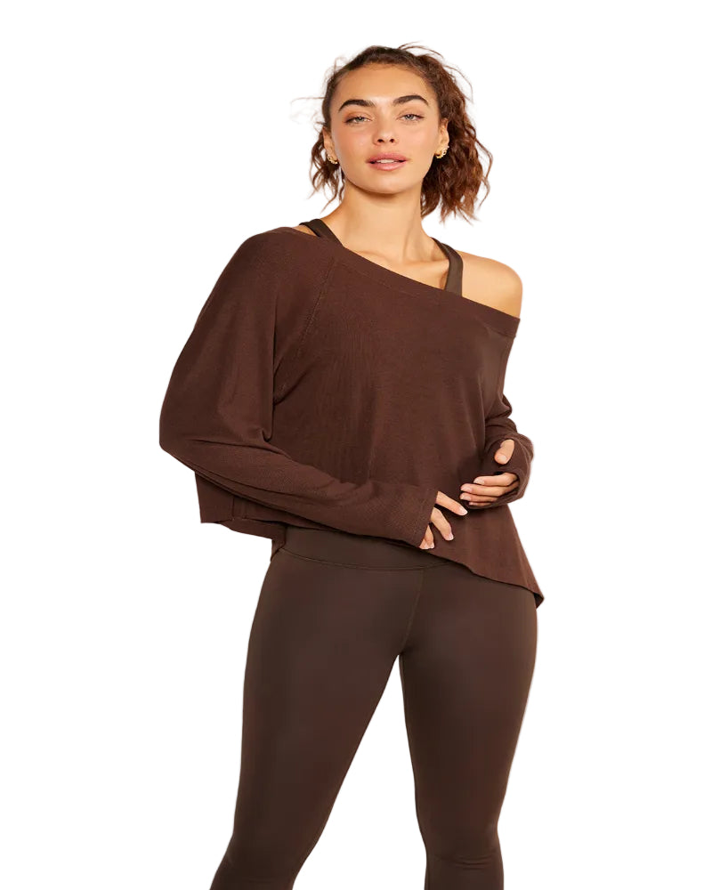 Woman wearing a brown off-shoulder top and leggings against a white background