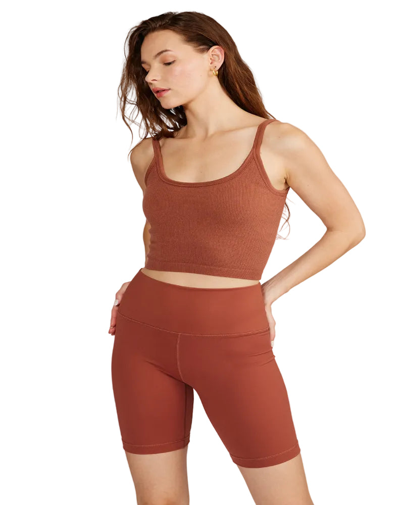 Woman wearing a brown athletic outfit on a light gray background