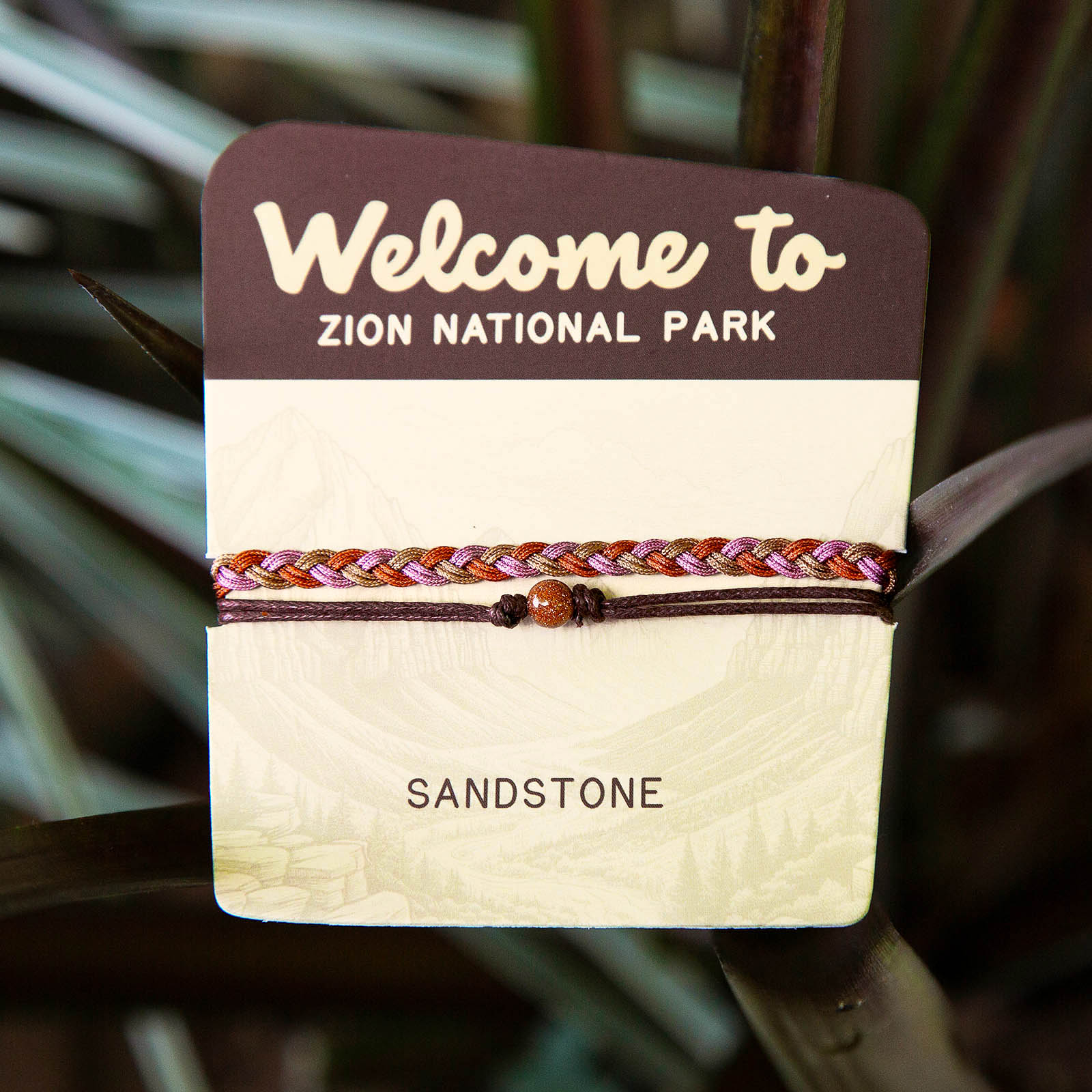 Bracelet on a card with 'Welcome to Zion National Park' text and 'Sandstone' label.