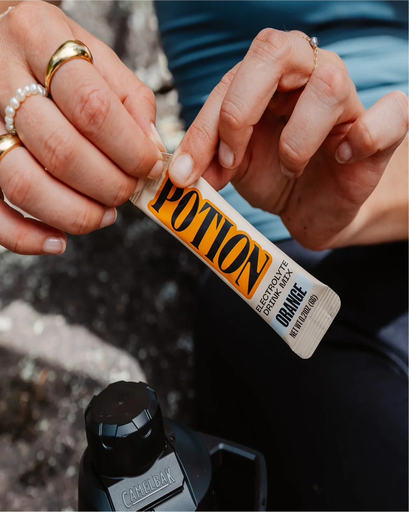 Person holding a tube of 'Potion' wax with a blurred background