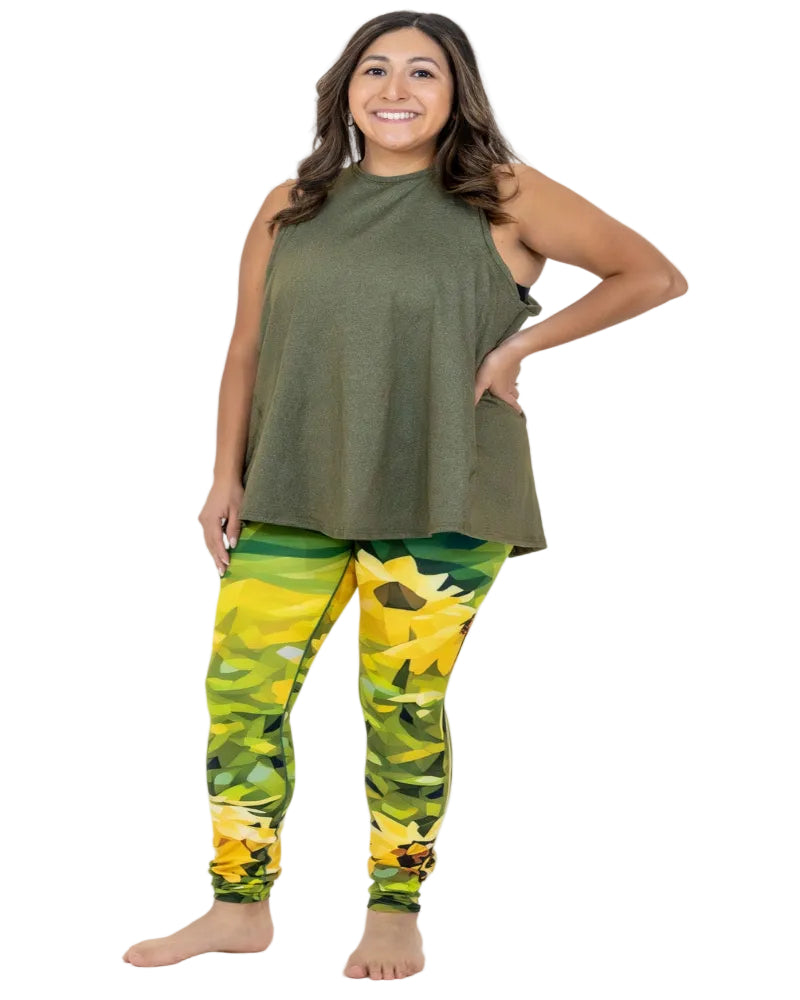 Woman wearing an olive green sleeveless top and sunflower-patterned leggings on a white background