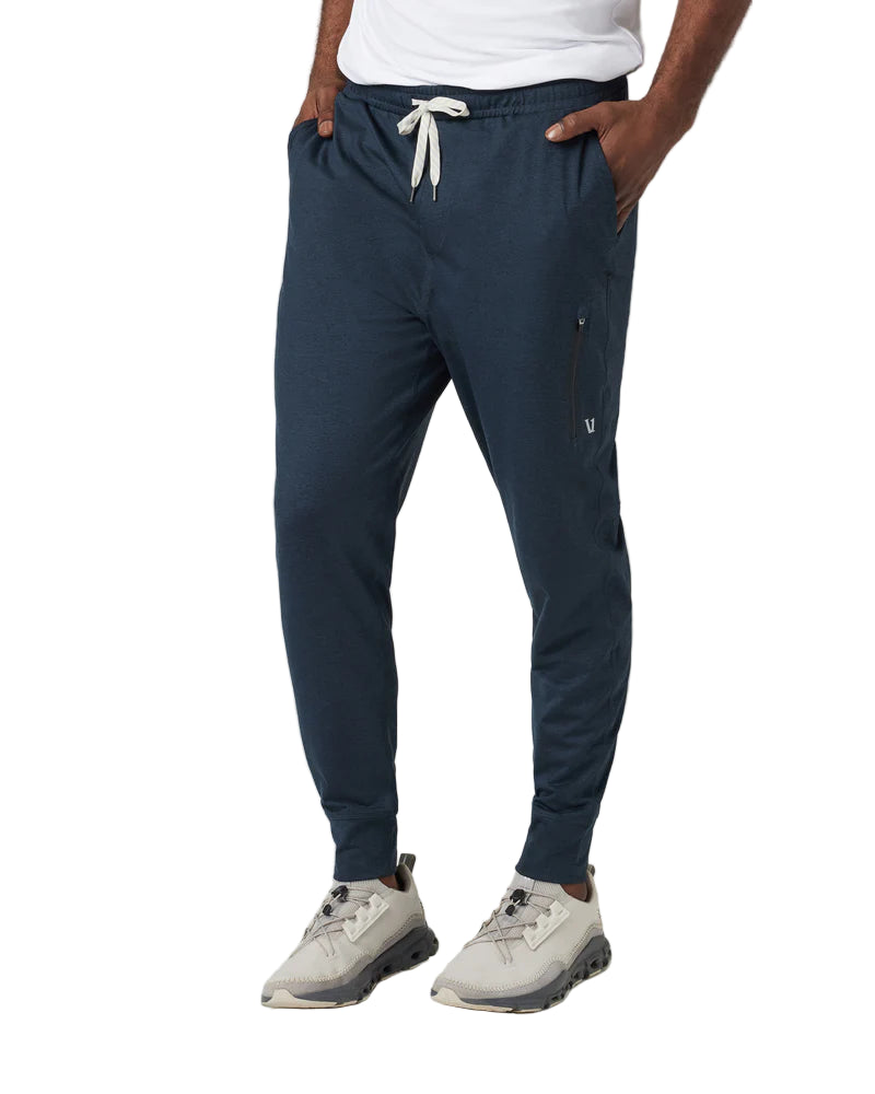 Person wearing navy jogger pants with a white background
