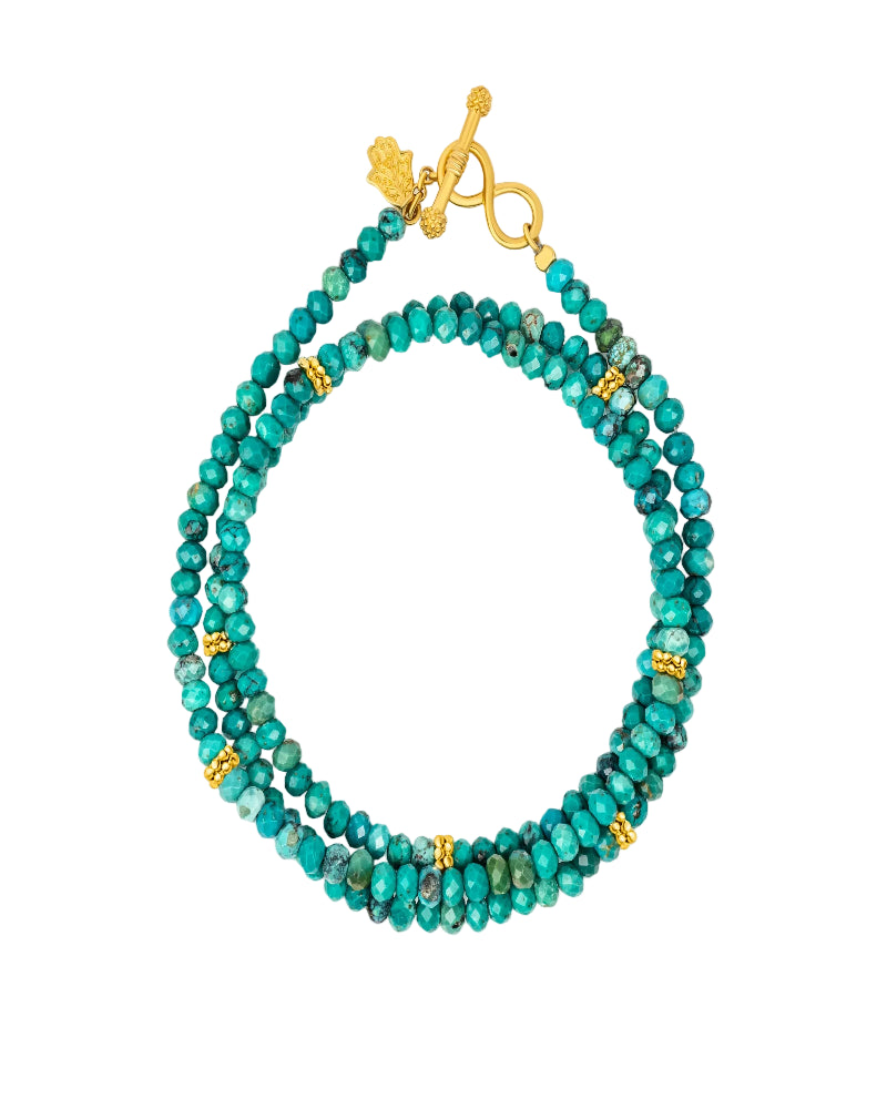 Turquoise beaded bracelet with gold accents on a white background
