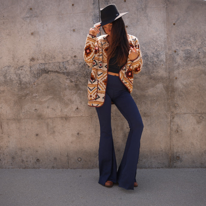 Woman wearing Teeki high-waisted bell bottom pants styled with boots and casual top