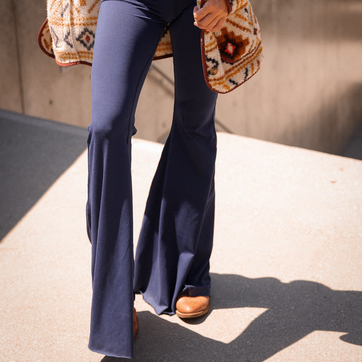 Navy blue flared pants worn by a person on a concrete surface.