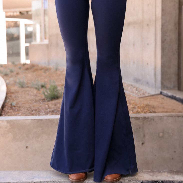 Navy blue flared pants worn by a person standing on a concrete surface with a blurred background.
