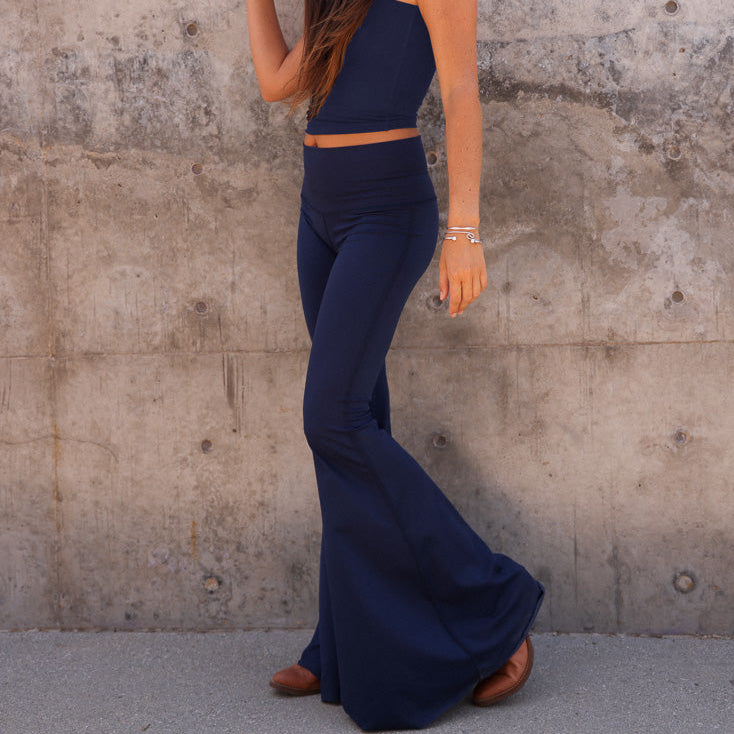 Person wearing a navy blue outfit against a textured wall.