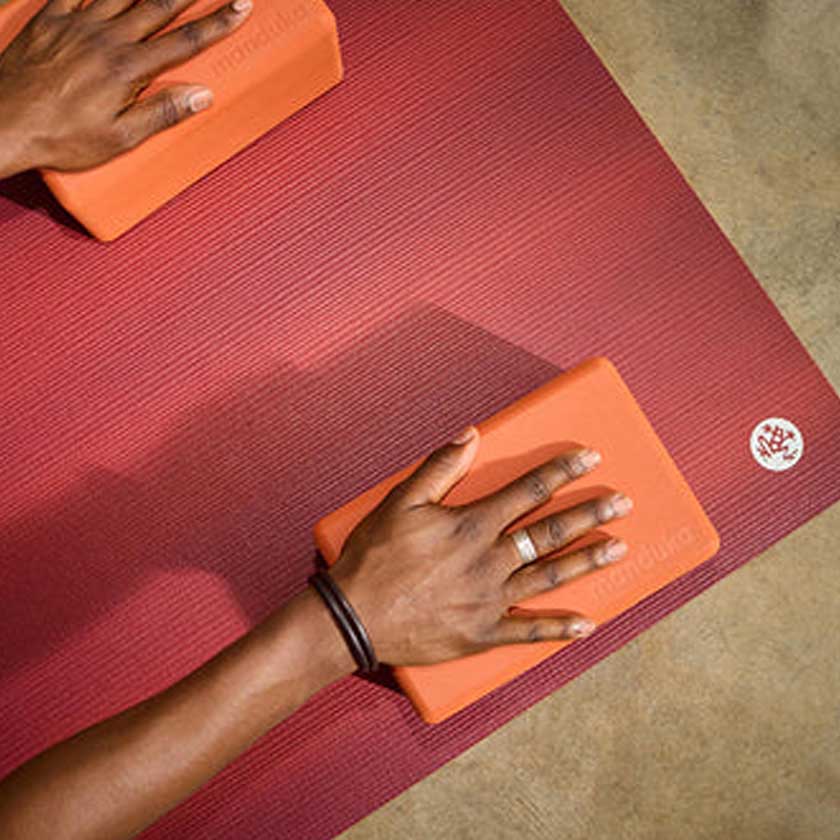 Person using orange yoga blocks on a red yoga mat
