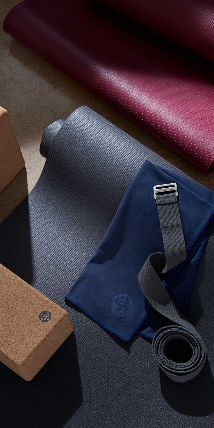 Yoga mat, block, and strap on a dark surface