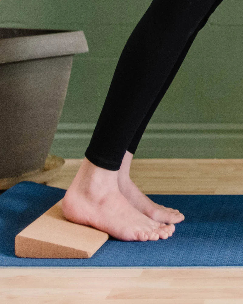 Person using a wooden block on a blue mat with a green wall in the background