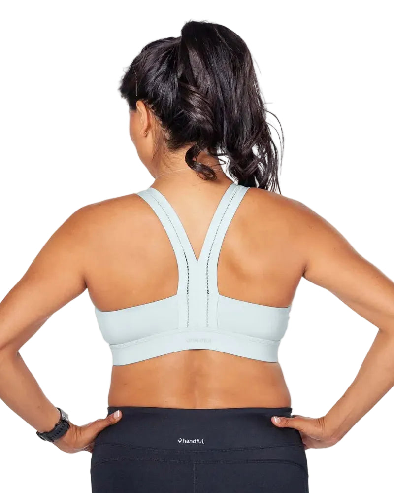 Woman wearing a light blue sports bra and black leggings on a white background