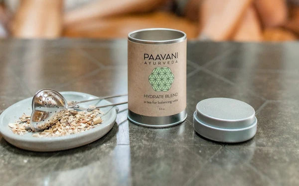 PAAVANI AYURVEDA product canister on a table with a spoon and plate of food.