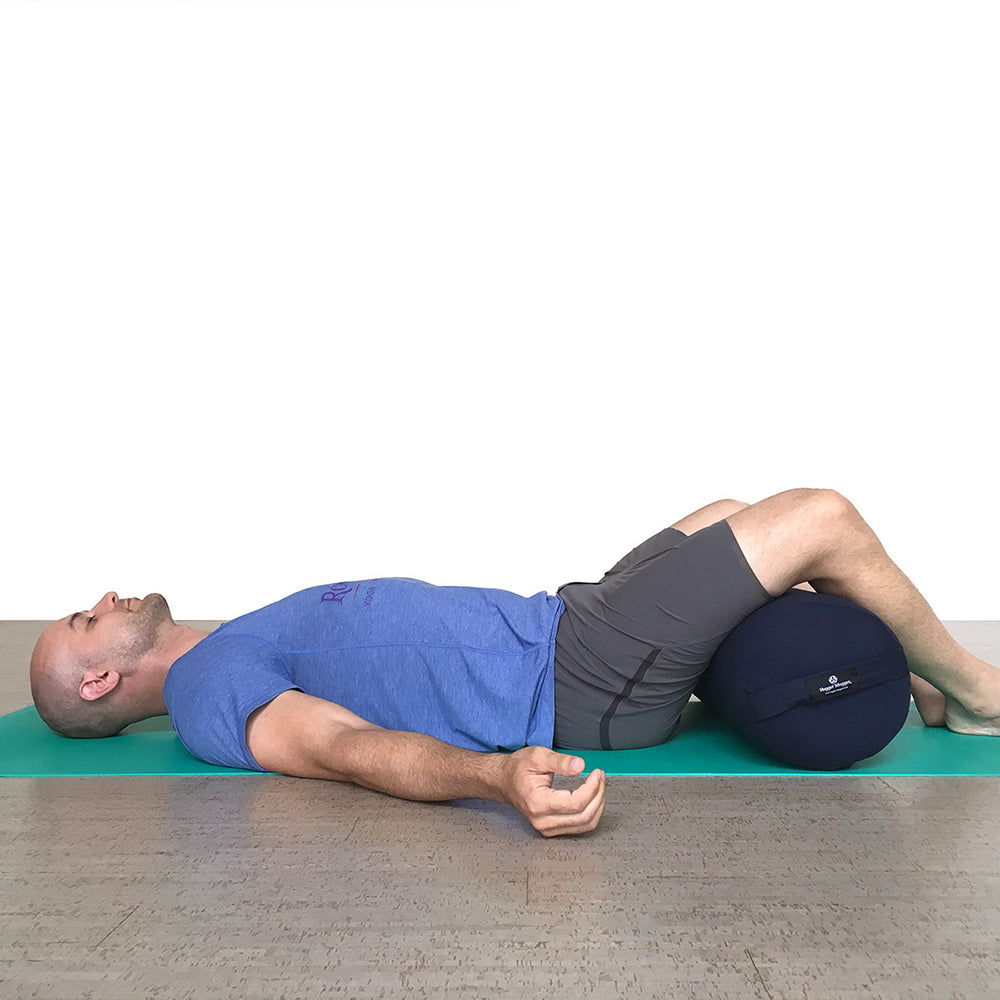 Person using a foam roller on a yoga mat with a white background