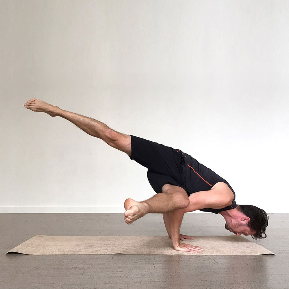Person performing a yoga pose on a mat with a plain background