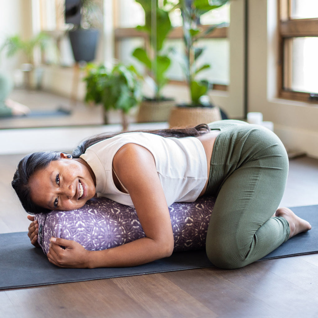 Woman practicing yoga on a mat with plants in the background