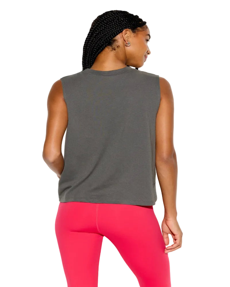 Person wearing a gray sleeveless top and pink leggings on a white background