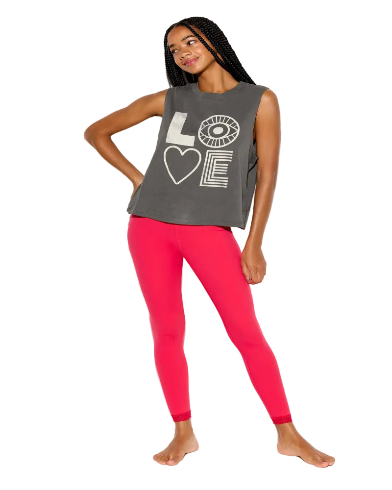 Woman wearing a gray tank top with a heart design and pink leggings on a white background