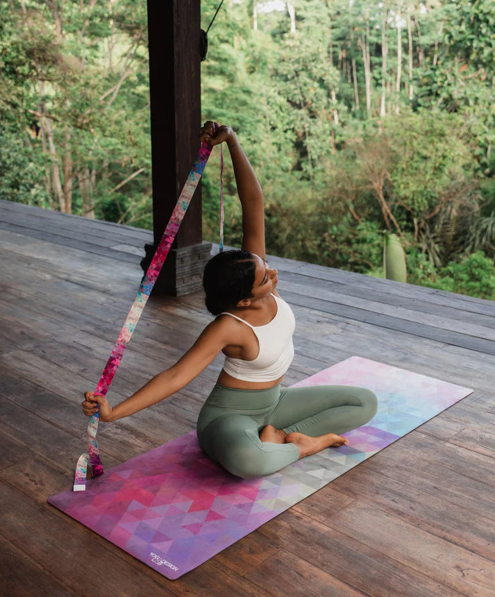 Person practicing yoga on a colorful mat with a scenic background